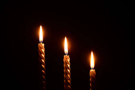Three golden candles on a black backgroundの写真素材