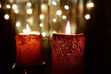 Two orange candles over christmas lights