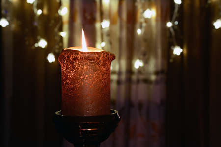 Orange candle over christmas lightsの写真素材