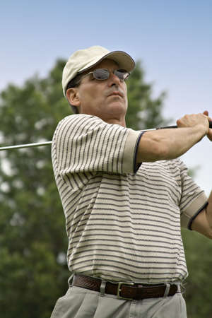 Close up of man as golf swing is completed.の写真素材