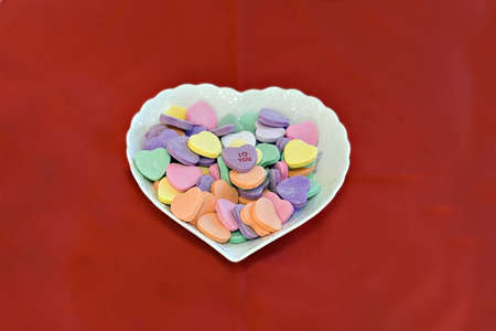 Heart shaped dish of conversation hearts.  I love you on top.の写真素材