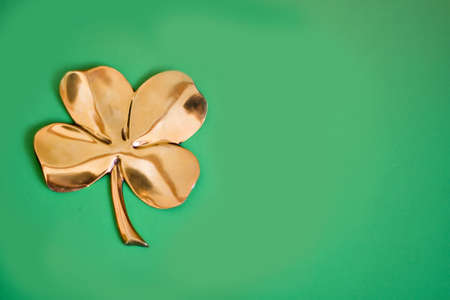 A gold four-leaf clover on a green background.の写真素材