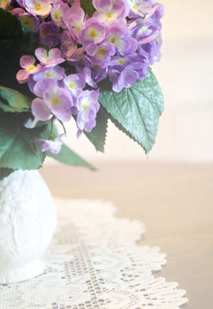 Pitcher of hydrangea with doily on table.  Shallow depth of field.の写真素材