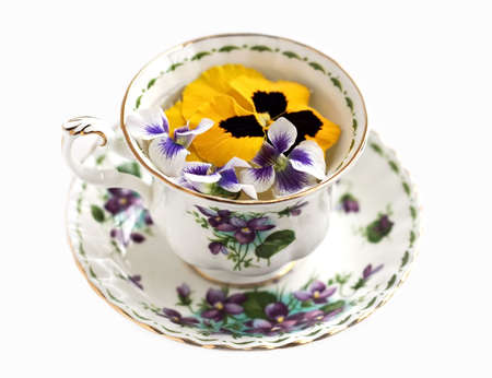 A violet embellished teacup filled with floating violets and pansies. の写真素材