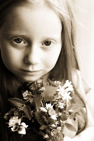 A small girl with long hair holding a bouquet of flowers の写真素材