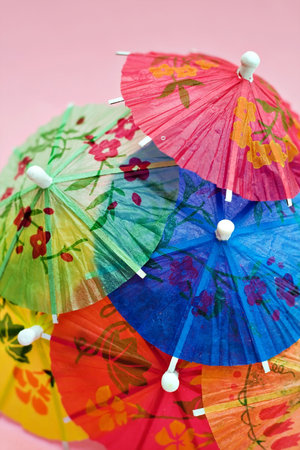 A grouping of colorful party drink umbrellas against a pink background.の写真素材