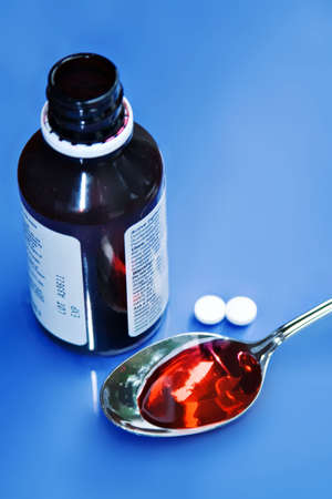 Medical concept - two aspirin and some cough medicine.の写真素材