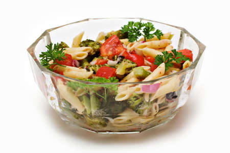 A clear glass bowl of fresh garden pasta salad on white background.の写真素材