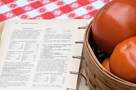 Cookbook of tomato recipes next to a basket of my fresh garden tomatoes.  の写真素材