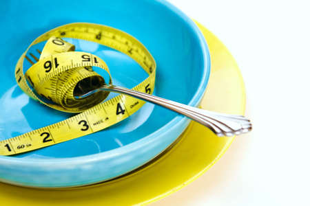 Concept shot of a weighl loss - health issues. tape measure wrapped around fork in bowlの写真素材