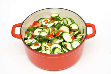 A large cast iron enambled pot filled with fresh garden chopped zuchinni, red peppers, green peppers, onions and garlic being prepared for a pasta sauce.の写真素材