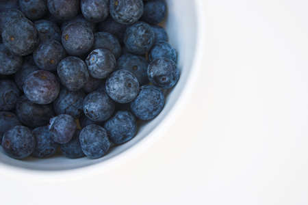 Very blueberries in a bowl, isolated against a very light grey backgroundの写真素材
