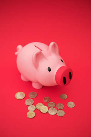 Piggy bank on red & assorted British coins - shallow dofの写真素材