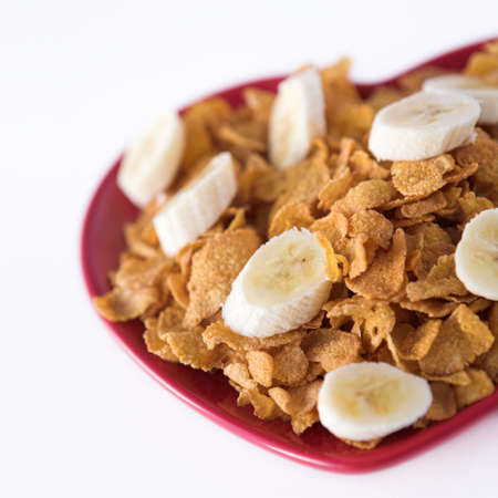 Cornflakes & sliced banana on a heart shaped plate - healthy eating concept. Shallow dofの写真素材