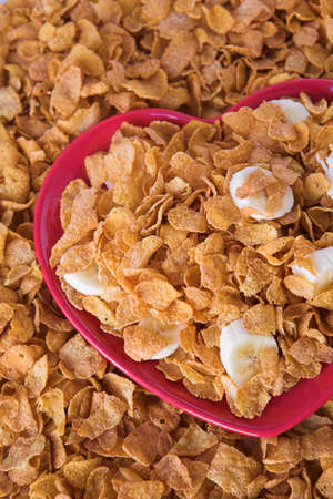 Cornflakes & sliced banana on a heart shaped plate - healthy eating conceptの写真素材