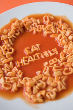 Eating healthily spelt out in pasta letters & tomato sauce - health food conceptの写真素材