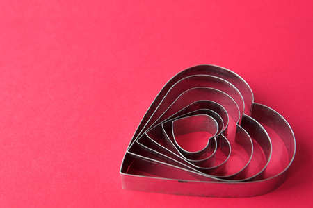 Heart shaped cookies cutters on a red background with intentional space for copy - shallow dofの写真素材