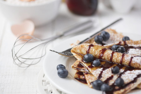 Freshly prepared crepes with blueberries & chocolate sauce - shallow dof