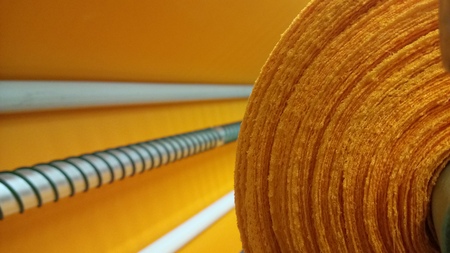 New industrial orange roll, orange background. Concept: material, fabric, manufacture, garment factory, new samples of fabrics.の写真素材