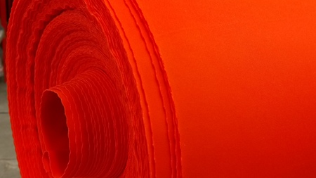 New industrial red roll, red background. Concept: material, fabric, manufacture, garment factory, new samples of fabrics.の写真素材