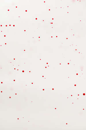 Small red bubbles floating on a white backgroundの写真素材