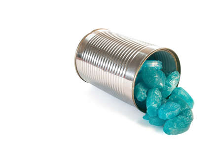 Blue sweets falling out of a small tin canの写真素材