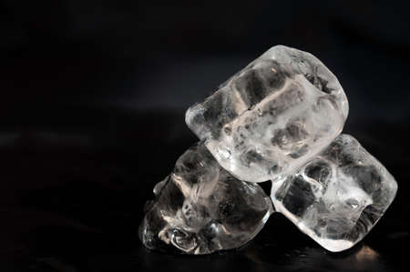 Three ice cubs laying on black pices of silk fabricの写真素材