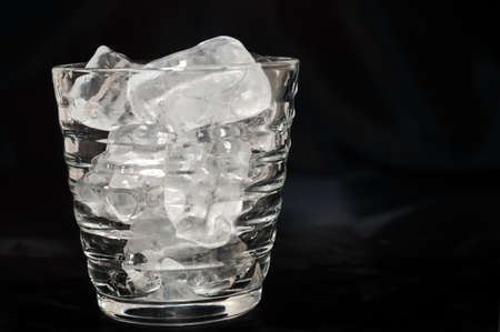Glass of water with ice cube over a black backgroundの写真素材