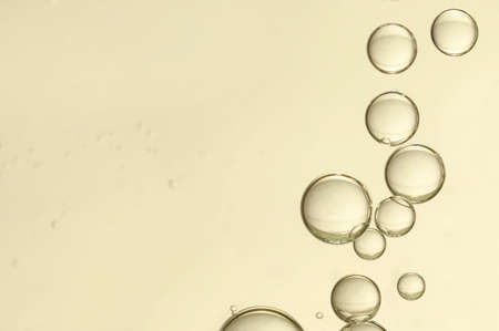Golden fizz  bubbles flows over a light backgroundの写真素材