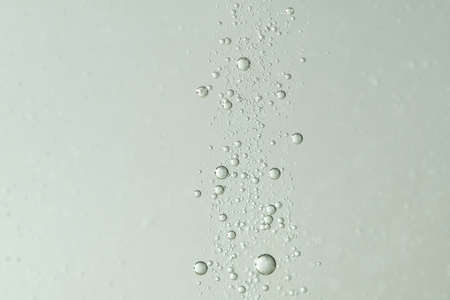 A cascade of water bubbles over a blurred background.の写真素材