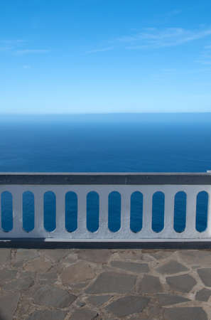 A white and gray fence infront of the beautil ocean.の写真素材