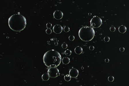 Shiny water bubbles flows over a dark surface.の写真素材