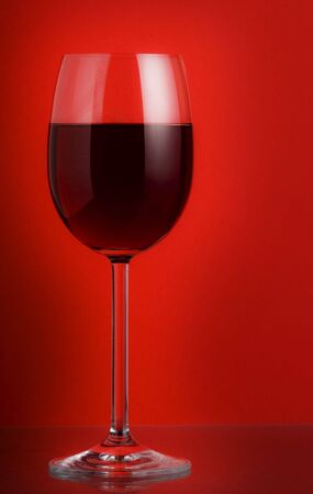 glass of red wine on red backgroundの写真素材