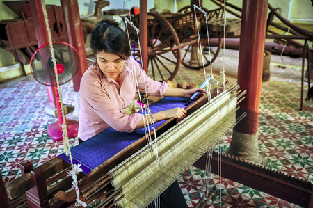 PHNOMPENH, CAMBODIA - FEBRUARY 09, 2014 - A woman weaver adjusts the silk cloth on her loom in Cambodia. Weaving is one of traditional careers in Cambodia.のeditorial素材