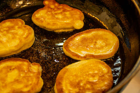 Appetizing pancakes in a black pan are almost readyの写真素材