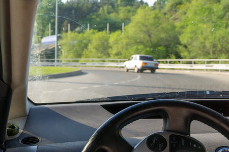 steering wheel and windshield with stains from the wipers, the car moves in a circular motion,...