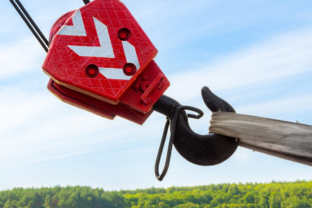 the red hook of truck crane is stretched with a sling for transportation against the background of...