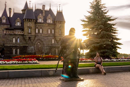Khryashchevka, Russia, July 16, 2020, girl is photographed against background of castle and statue of knight, backlightのeditorial素材