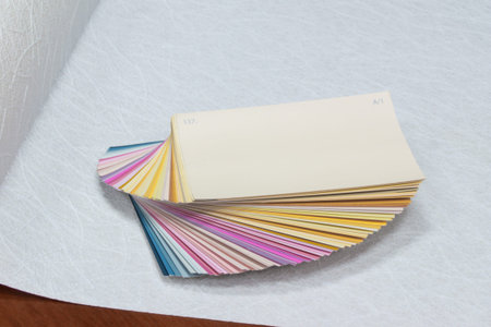 color palette cards without their names lie on the wallpaper for painting, selective focus