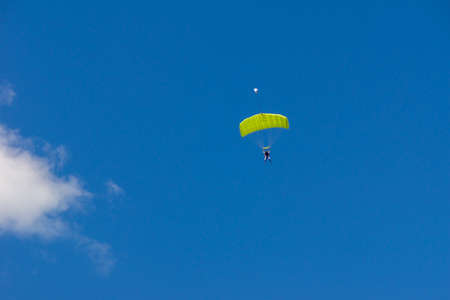 tandem jump of an amateur with a trainer under a canopy of a green parachute-wingの写真素材