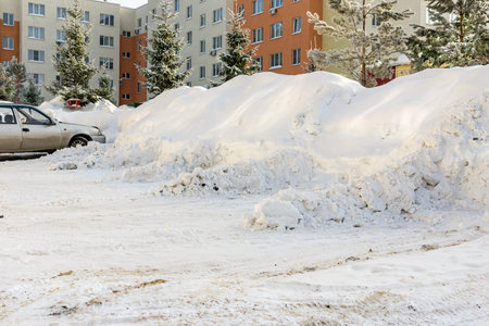 a lot of snow in the courtyard of a multi-storey building, trees and parking lots covered with snow...