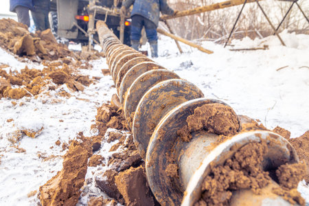 a drill auger is lying on the snow in the clay after deep exploration of the frozen soil, selective...