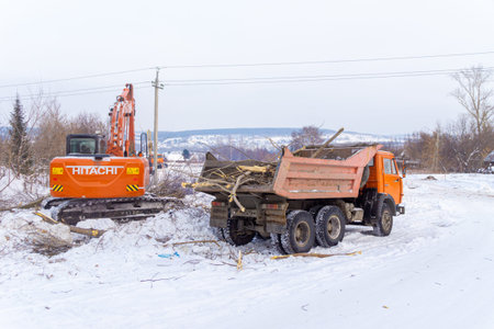 23 january 2021, Kemerovo, Russia. Clearing bushes and undergrowth of the construction site with an orange Hitachi excavatorのeditorial素材