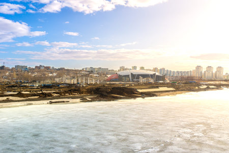 On banks of river covered with ice, complex of buildings for outdoor activities is under...
