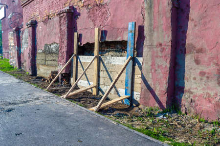 a temporary retaining wall made of boards serves as a formwork for a concrete patch in a brick wall that is collapsing from moisture, selective focusの写真素材