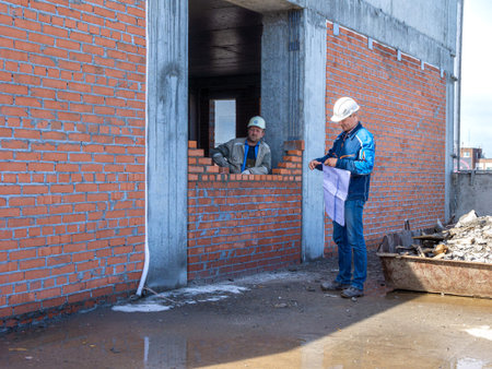 Kemerovo, Russia - 24 june 2021. Foreman with construction drawings checks the quality of work of a...