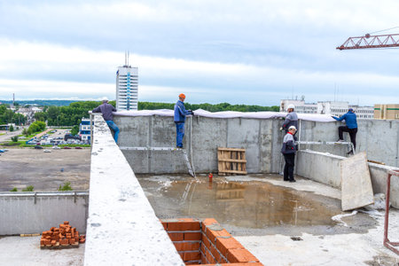 Kemerovo, Russia - 24 june 2021. On roof of building workers are pulling protective construction...