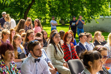 Russia, Kemerovo - 07, 2021. People in the auditorium in the open air, among them two young women see that they are being photographed and smile kindly, selective focusのeditorial素材