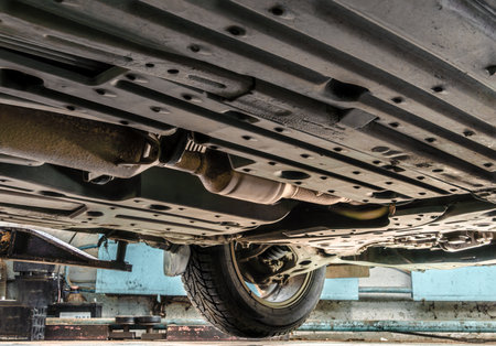 The car at the service station bottom view is visible - the lower surface of the passenger car, the bottom of the car with the exhaust system and the front beam, selective focusの写真素材