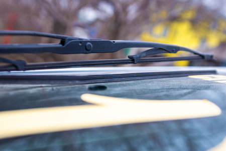 Close-up of worn-out windshield wiper blades with peeling rubber, showing they are no longer effective and should be replaced soon, especially before autumn rains with selective focus on damaged edgeの写真素材